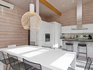 Una cocina moderna con armarios blancos, una campana extractora de acero inoxidable y una zona de bar con taburetes.