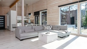 Een moderne woonkamer met een modulaire bank, een witte salontafel en een grote schuifpui naar een buitenruimte.