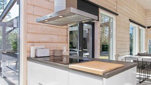 Een moderne keuken met een groot schiereiland, houten lambrisering en uitzicht op het buiten.