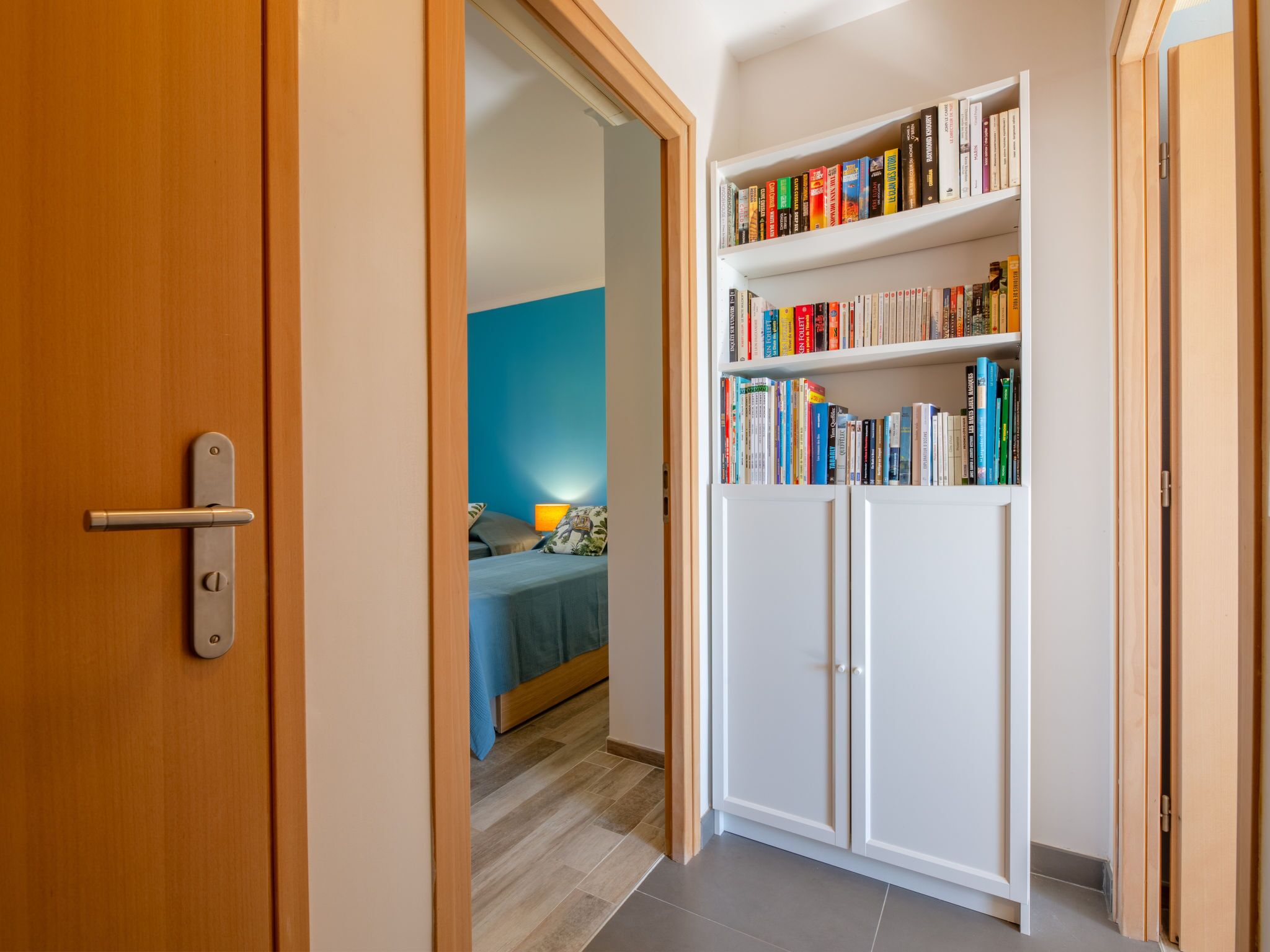 Ein Zimmer mit einem Bett, einem Bücherregal und einer Tür.