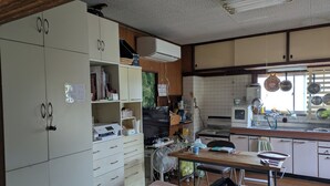 A kitchen with white cabinets, a wooden table, and a fan.