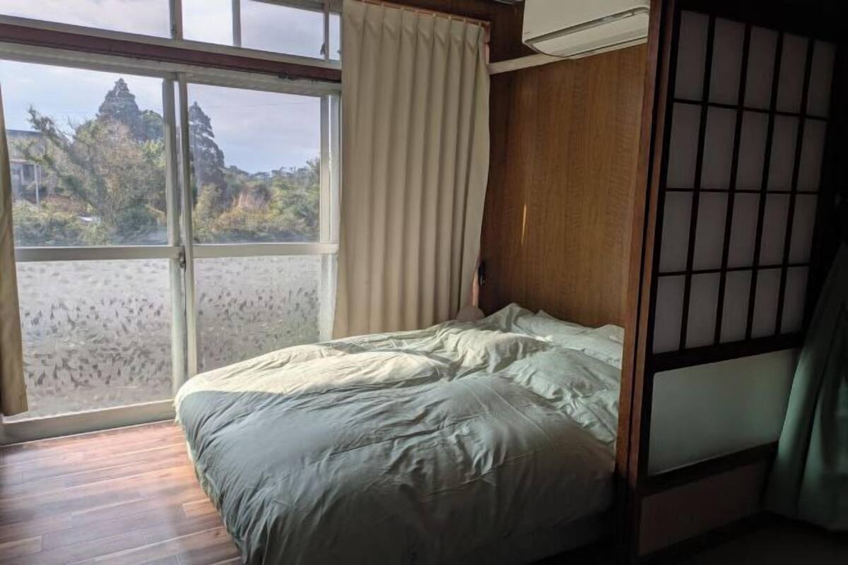 Une chambre dotée d’un lit, d’une porte-fenêtre coulissante, d’une vue sur un paysage rocheux et d’une cloison de style japonais traditionnel.