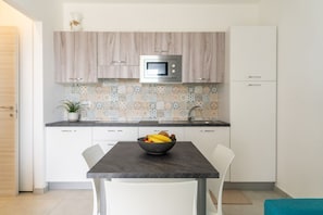 Une cuisine moderne équipée d’un four à micro-ondes, avec un saladier de fruits posé sur le comptoir et une plante en pot.