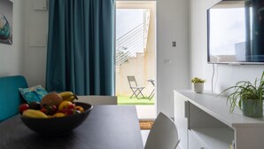 Una sala de estar moderna con una mesa de comedor, un frutero, un sofá, un televisor y vistas al exterior.