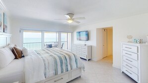 Une chambre avec un lit, une télévision, une commode et un balcon donnant sur la mer.