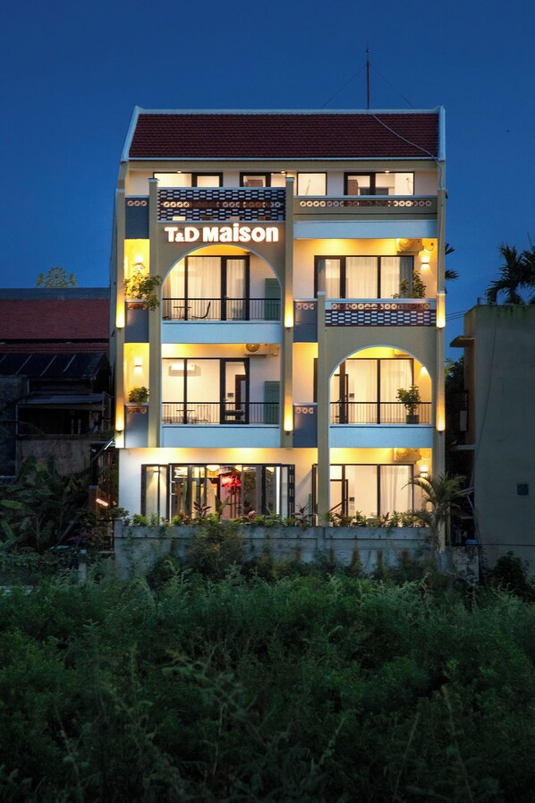 Un immeuble à plusieurs étages, doté de balcons et de grandes fenêtres, portant l’inscription « T.D Maison ».