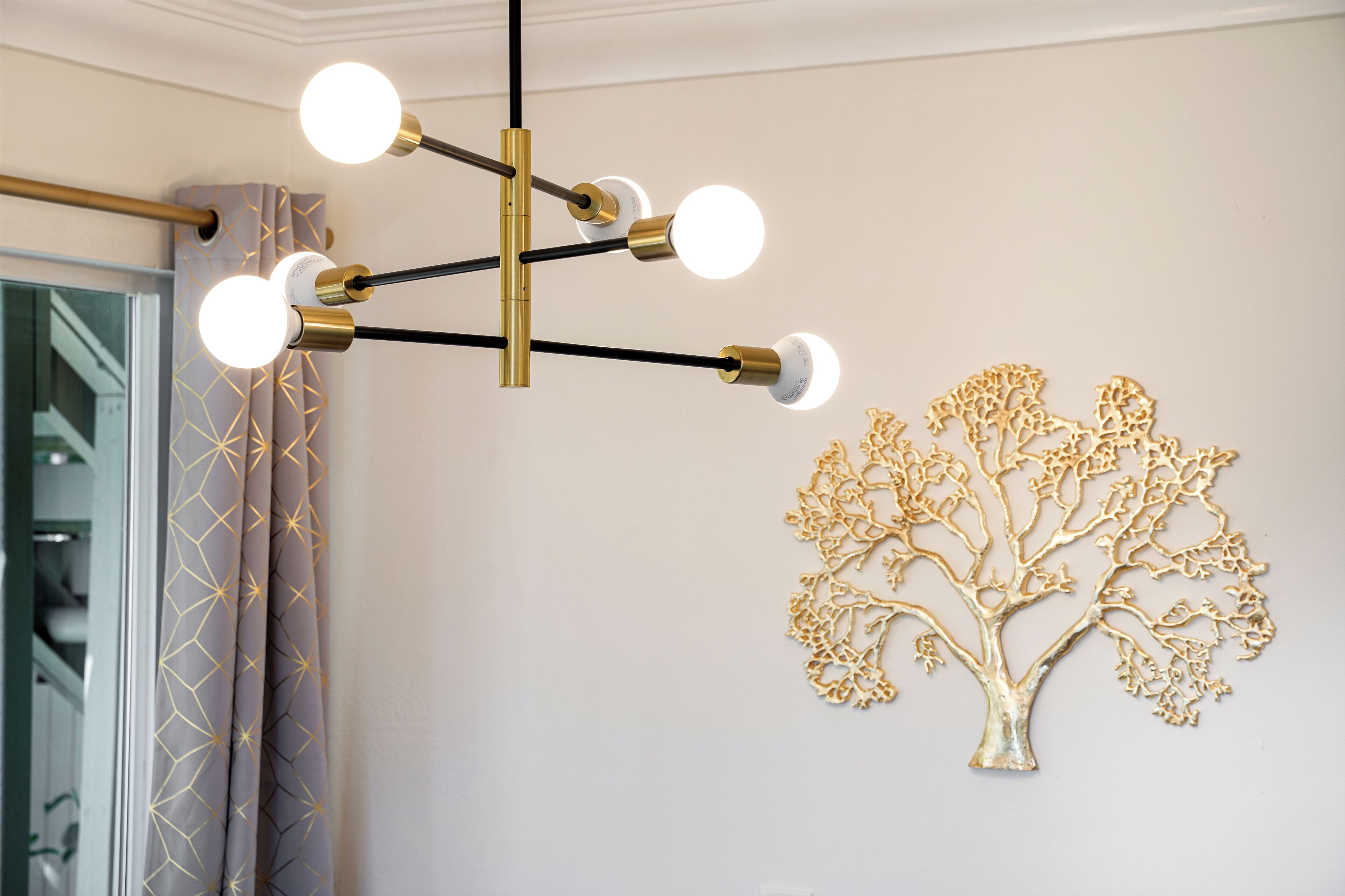 Ein Kronleuchter mit mehreren Lampen und ein an der Wand befestigtes Baumdekor.