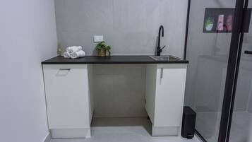 A compact bathroom with a sink, two cabinets, a towel rack, and a small potted plant.