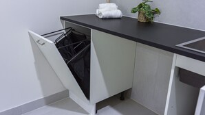 Une salle de bain moderne équipée d’un lave-linge intégré, d’un porte-serviettes et d’une plante en pot.