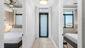 A hotel room with a bed, a desk, a chair, a window, and a door. - Hi3051hl203: 3 Bed, Seascape (Melbourne Beach)