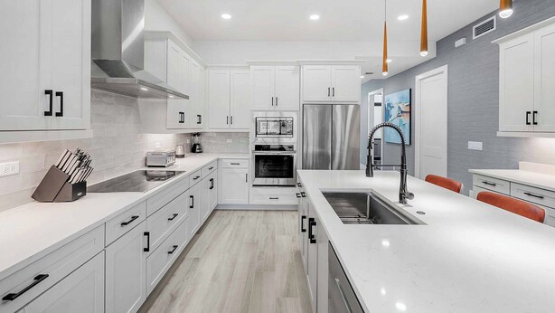 A modern kitchen with white cabinetry, stainless steel appliances, and a central island with a sink. - Hi3051hl203: 3 Bed, Seascape (Melbourne Beach)
