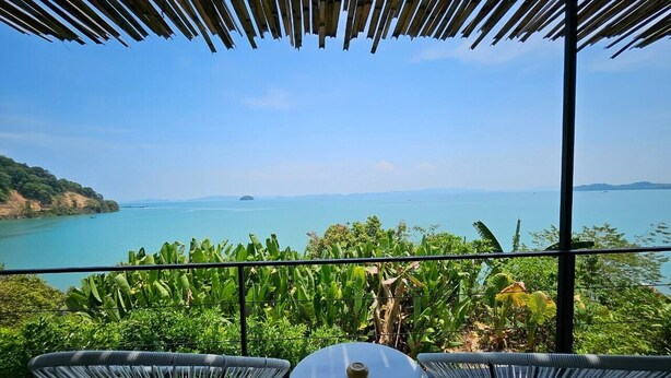 Un balcon donnant sur la mer, entouré d’une végétation luxuriante.