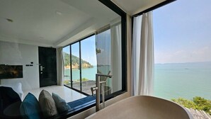 Une chambre moderne dotée d’une grande fenêtre donnant sur un plan d’eau et d’un balcon.