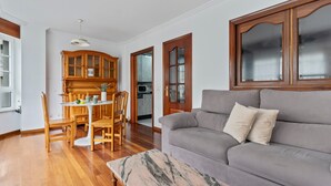Een woonkamer met een grijze bank, een houten eettafel, stoelen en een marmeren salontafel.