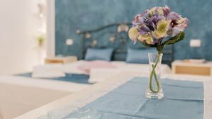 Ein Schlafzimmer mit einem Bett, einer Blumenvase und einer blauen Wand.