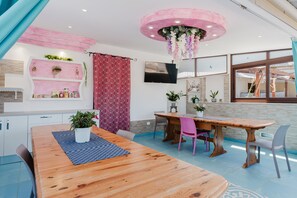 Un comedor moderno con una mesa de madera, sillas y un televisor montado en la pared.