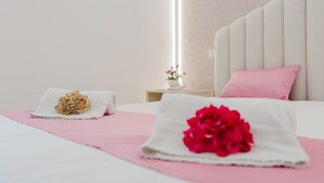 A neatly made bed with pink bedding, a white headboard, and a bedside table with a lamp and a small vase with flowers. - Bed and Breakfast 'Le Ortensie Rosa' with Shared Terrace, Wi-Fi and Air Conditioning (San Vito Lo Capo)