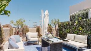 An outdoor patio with wicker furniture, a glass-top table, and a variety of potted plants. - Bed and Breakfast 'Le Ortensie Rosa' with Shared Terrace, Wi-Fi and Air Conditioning (San Vito Lo Capo)