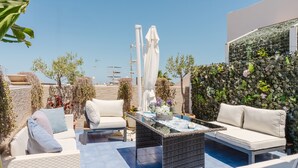A rooftop patio with outdoor furniture, a glass-top table, and a decorative wall. - Bed and Breakfast 'Le Ortensie Verde' with Shared Terrace, Wi-Fi and Air Conditioning (San Vito Lo Capo)