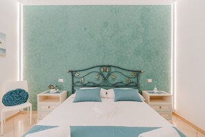 A bedroom with a bed, two nightstands, a chair, and a wall with a textured pattern.
