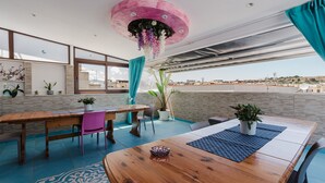 A dining area with a wooden table, chairs, potted plants, and a view of the cityscape. - Bed and Breakfast 'Le Ortensie Verde' with Shared Terrace, Wi-Fi and Air Conditioning (San Vito Lo Capo)