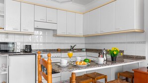 A modern kitchen with white cabinets, a granite countertop, and a breakfast bar with wicker chairs.