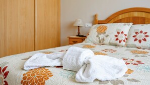 Una cama bien hecha con ropa de cama floral, un cabecero de madera y una mesita de noche con una lámpara.