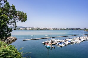 Una marina con imbarcazioni ormeggiate, un ponte sullo sfondo e un cielo sereno.
