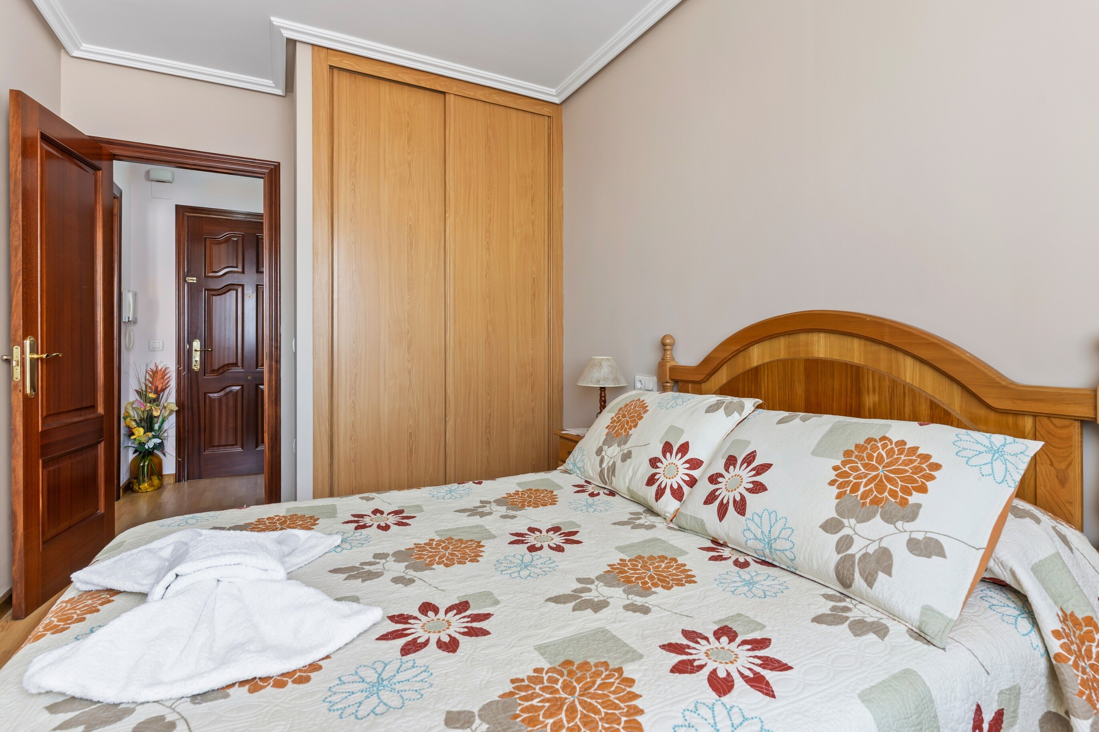 Un dormitorio con cama, cabecera de madera y armario.