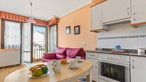 Una cocina con una mesa de comedor, horno y un sofá rosa.