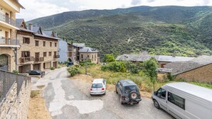 Ein Wohngebiet mit befestigter Straße, parkenden Autos und Häusern mit Balkonen.