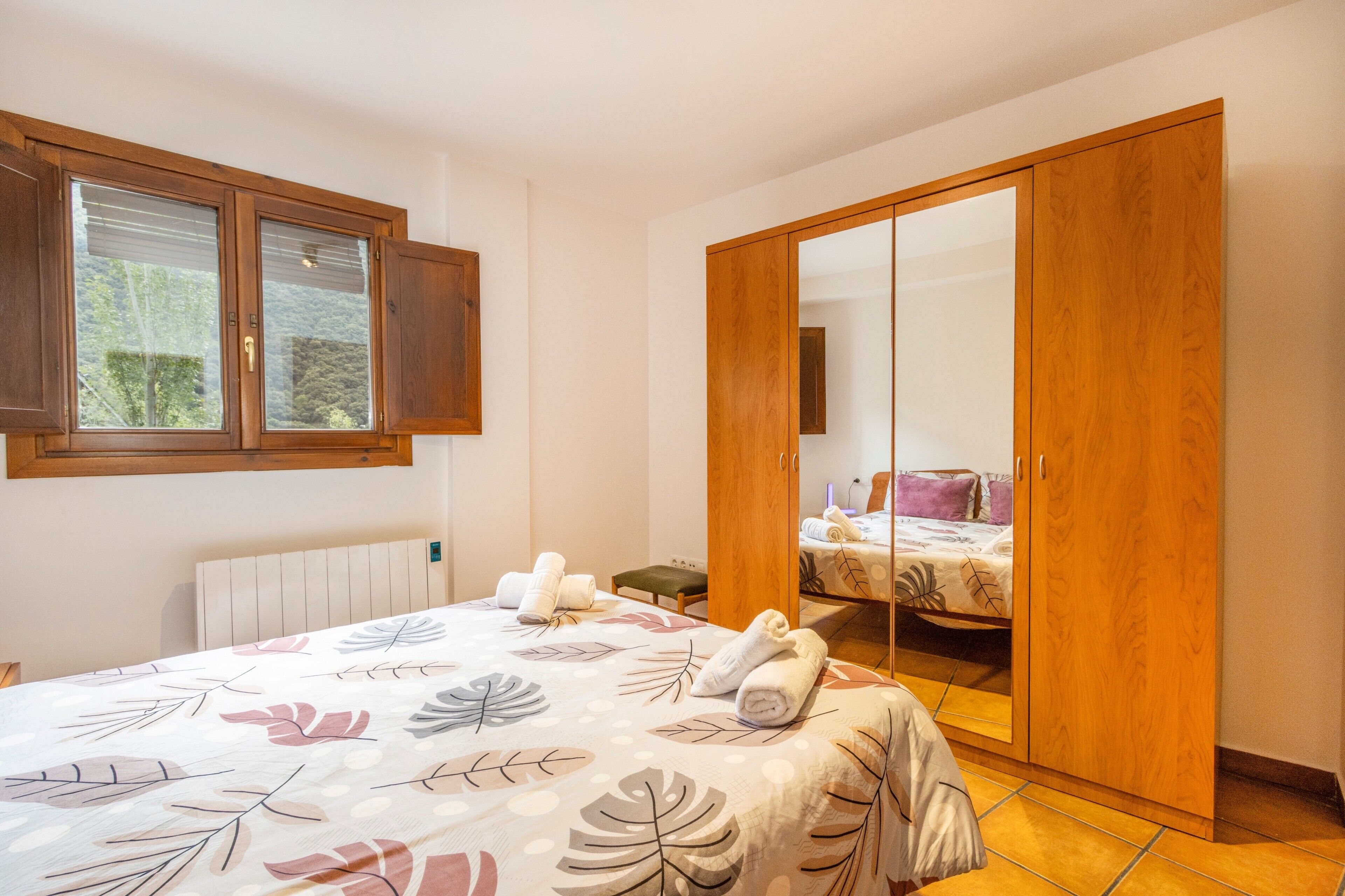A bedroom with a bed, a wardrobe, a window, and a radiator.