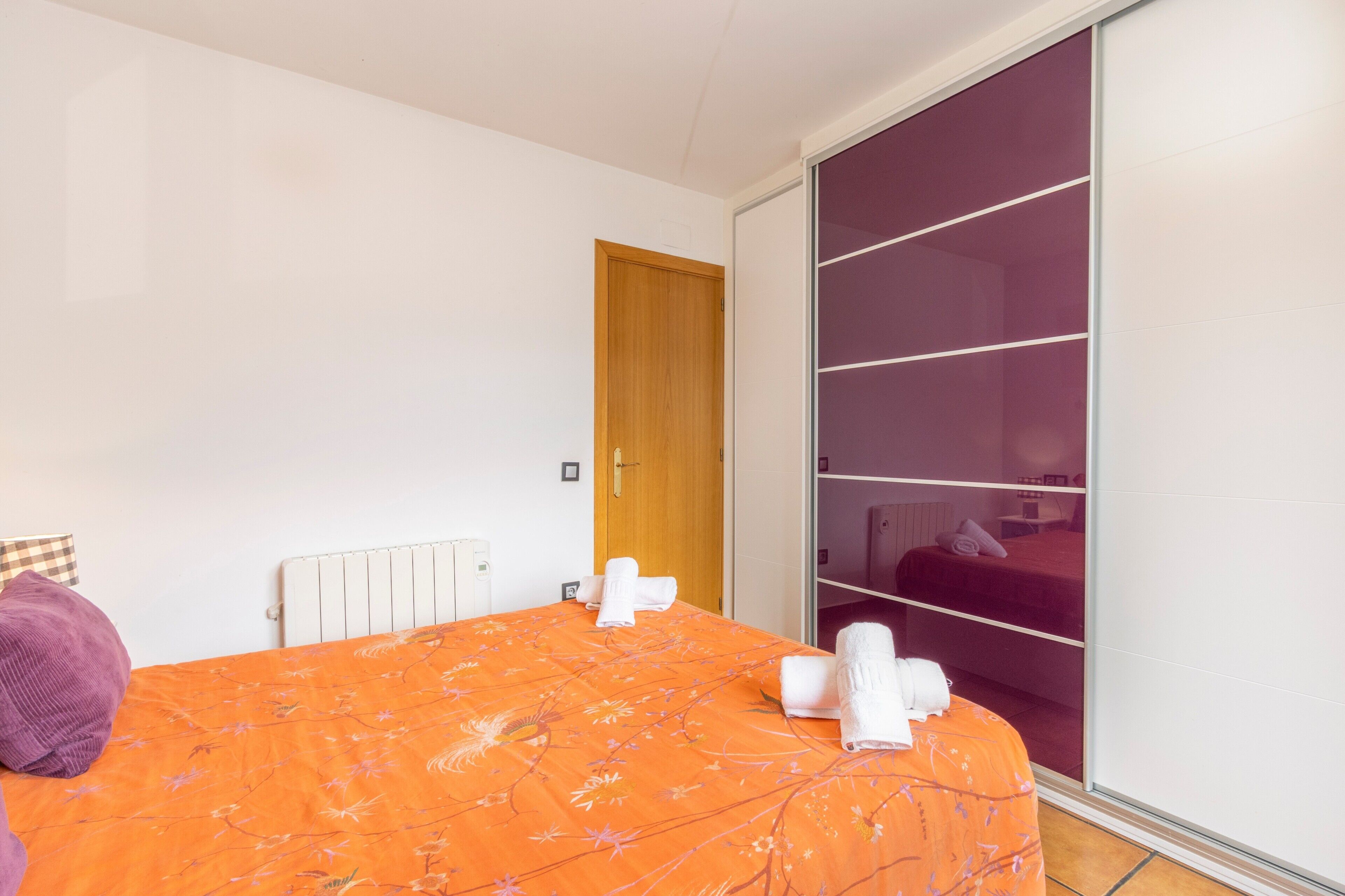 Une chambre à coucher avec un lit, une porte en bois, une armoire et un radiateur.