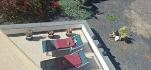 Une terrasse sur le toit, aménagée avec des chaises longues, des plantes en pot et une piscine.