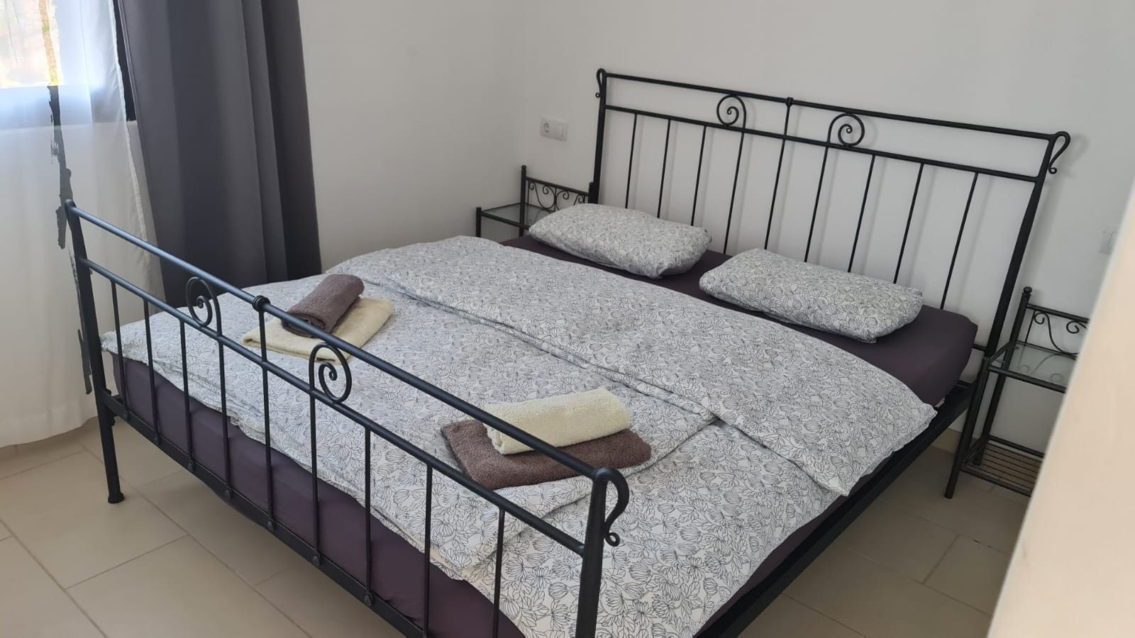 A single bed with a metal frame, a patterned bedspread, and pillows.