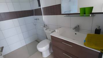 A bathroom with a shower, toilet, and vanity with drawers.