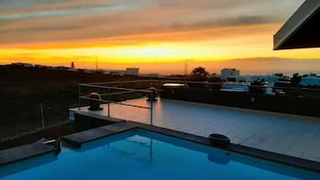 Une piscine sur le toit offrant une vue sur le coucher de soleil et les bâtiments environnants.