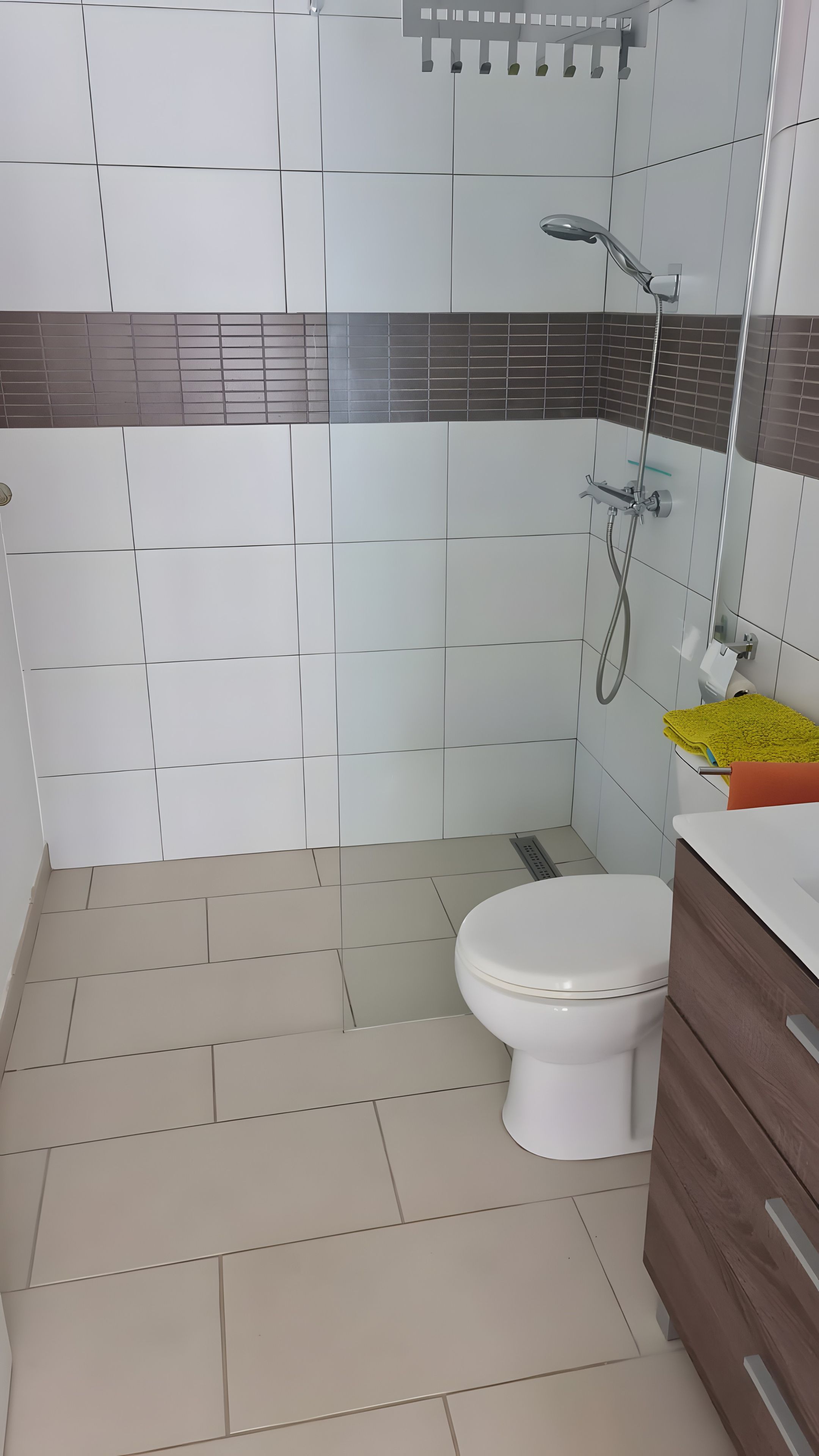 Une salle de bain avec des toilettes, une douche et un lavabo, ainsi qu’une serviette jaune.