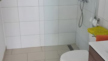 Une salle de bain avec des toilettes, une douche et un lavabo, ainsi qu’une serviette jaune.