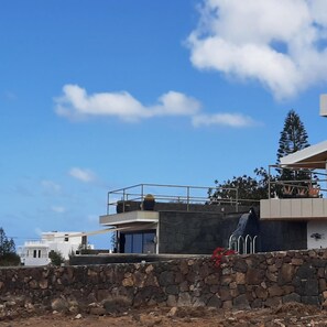 Un bâtiment moderne avec un mur en pierre, un balcon et un ciel d’un bleu éclatant.