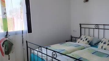 Ein Schlafzimmer mit einem Bett, einem Sessel und einem Fenster mit Vorhängen.