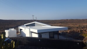A modern building with a flat roof and large windows, surrounded by a barren landscape. - Apartment Atlantis with Sea View, Wi-Fi and Air Conditioning (Las Breñas)