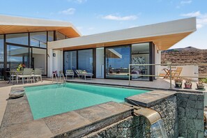 A modern house with a swimming pool, outdoor seating, and a view of the landscape. - Holiday Villa 'Atlantis' with Sea Views, Wi-Fi, and Air Conditioning (Las Breñas)