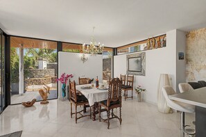 A dining area with a table set for four, surrounded by wooden chairs with cushioned seats. - Holiday Villa 'Atlantis' with Sea Views, Wi-Fi, and Air Conditioning (Las Breñas)