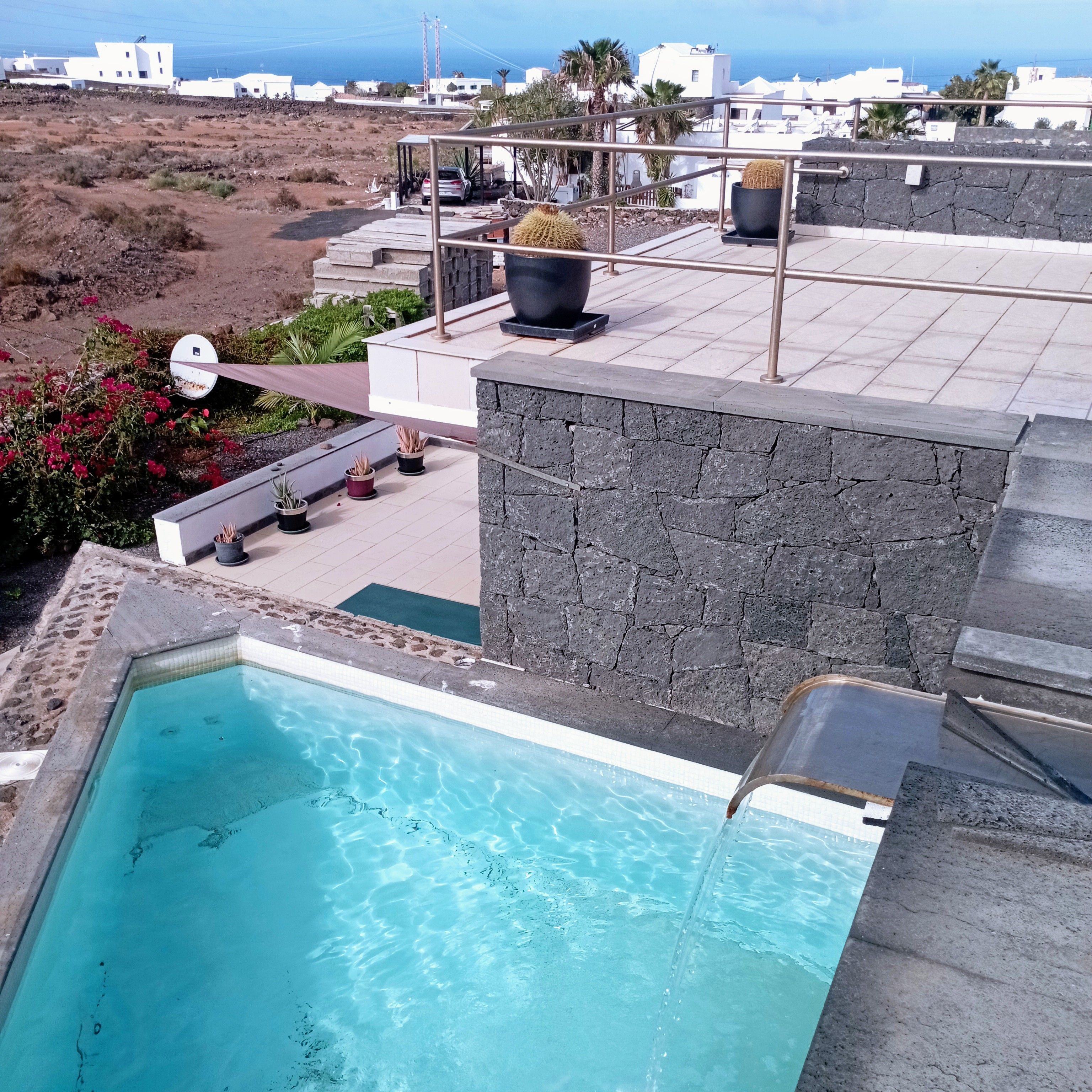 Ein Pool auf dem Dach mit klarem, blauem Wasser, umgeben von Steinmauern und Blumentöpfen.