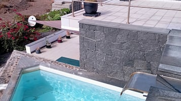 Ein Pool auf dem Dach mit klarem, blauem Wasser, umgeben von Steinmauern und Blumentöpfen.