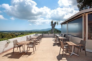 An outdoor patio with tables and chairs, overlooking a scenic landscape.