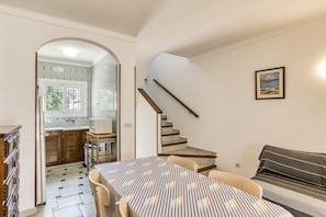 Un interior moderno con comedor, cocina y escalera.