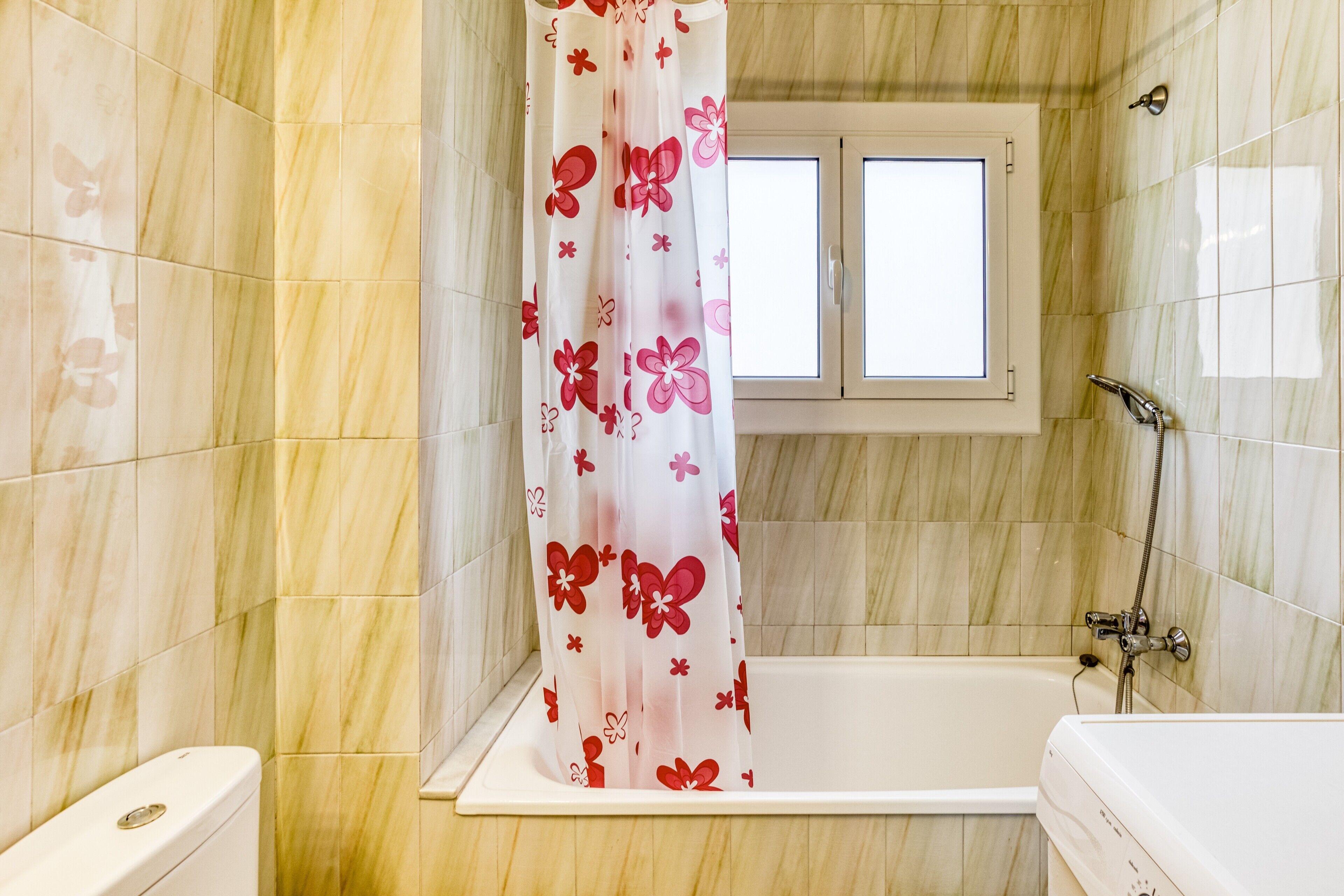 Une salle de bain avec une baignoire, une douche et une fenêtre.
