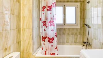 Une salle de bain avec une baignoire, une douche et une fenêtre.